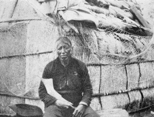 b. Outside an elm-bark structure. At the Ojibway village of Sagawamick, on south shore of Mille Lac, Minnesota. May 21, 1900